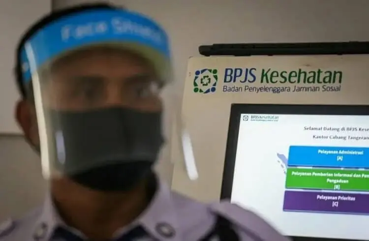 PAKAI PELINDUNG WAJAH : Petugas keamanan BPJS Kesehatan menggunakan pelindung wajah dan masker sesuai protokol Covid-19 di Kantor BPJS Kesehatan, Cikokol, Kota Tangerang, Rabu (1/7). (DEDE KURNIAWAN / SATELIT NEWS)