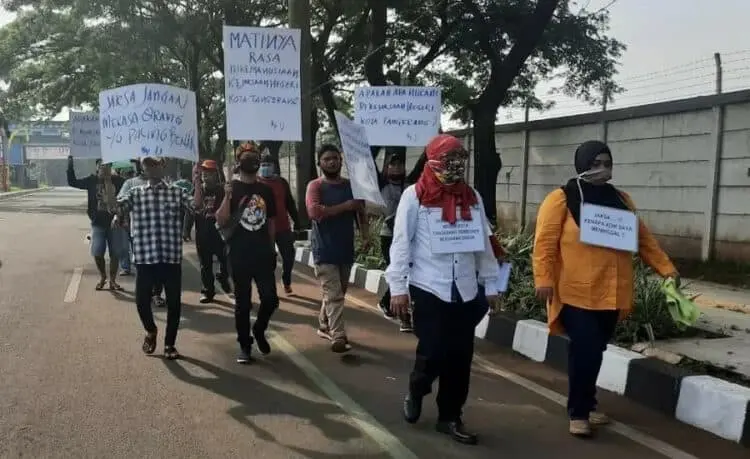 BAWA POSTER: Keluarga HG berjalan sembari membawa poster berisi tuntutan menuju Kejari Tangerang, Rabu (12/8). (IRFAN/SATELIT NEWS)