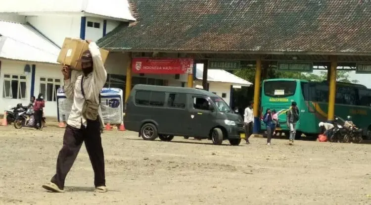 TERMINAL BUS: Penumpang yang turun dari bus di Terminal Labuan, sedang berjalan kaki sambi membawa barang bawaannya untuk kembali bergegas ke kediamannya, Senin (3/8). (NIPAL/SATELIT NEWS)