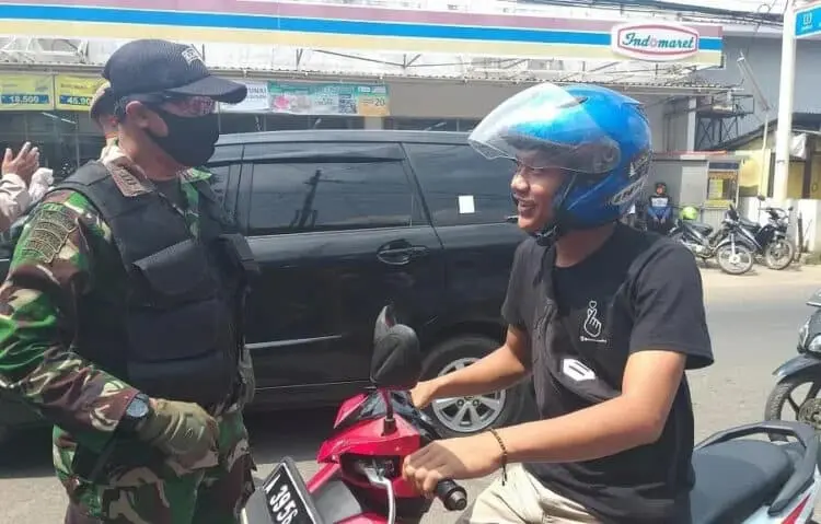 BERI PEMAHAMAN: Komandan Koramil 0101 Pandeglang, Kapten Inf Supandi, sedang memberikan pemahaman dan memberikan sanksi menyanyikan lagu kebangsaan kepada pengendara yang tak menggunakan masker di Jalan Raya Pandeglang-Labuan, Selasa (8/9). (NIPAL/SATELIT NEWS)