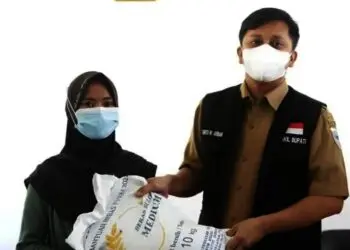 SERAHKAN BANTUAN BERAS–Wabup Pandeglang, Tanto Warsono Arban, secara simbolis menyerahkan bantuan beras kepada seorang KPM, di Aula Kantor Kecamatan Sindangresmi, Senin (26/7/2021). (ISTIMEWA)