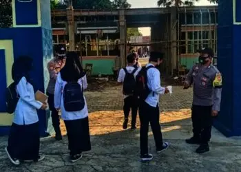 PENGAWASAN PROKES–Para personel Polsek Pandeglang Kota, sedang melakukan pengecekan suhu tubuh para siswa yang hendak mengikuti PTM, dan memberikan masker, di SMPN 1 Pandeglang, Jumat (10/9/2021). (NIPAL SUTIANA/SATELITNEWS.ID)