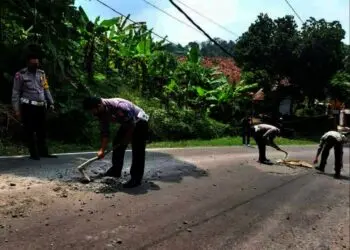 BERSIHKAN JALAN–Personel Satlantas Polres Pandeglang, sedang menyingkirkan limbah coran yang berserakan, di jalan AMD Lintas Timur Pandeglang, Selasa (28/9/2021). (ISTIMEWA)