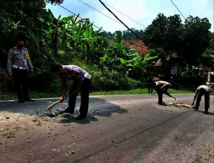 BERSIHKAN JALAN–Personel Satlantas Polres Pandeglang, sedang menyingkirkan limbah coran yang berserakan, di jalan AMD Lintas Timur Pandeglang, Selasa (28/9/2021). (ISTIMEWA)