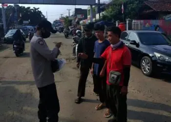 BAGIKAN MASKER–Personel Polsek Labuan, sedang membagikan masker kepada pengguna Jalan, di Jalan Raya Labuan-Carita, tepatnya di wilayah Pasar Labuan, Minggu (24/10/2021). (ISTIMEWA)