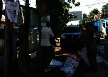 Anggota Satpol PP Pandeglang, menertibkan spanduk liar di Jalan Raya Pandeglang-Labuan, Jumat (26/11/2021). (ISTIMEWA)