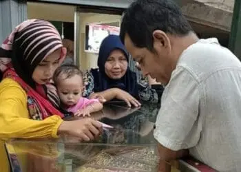 BELI EMAS–Emak-emak sedang membeli emas di toko emas yang ada di Pasar Badak Pandeglang, Selasa (19/4/2022). (NIPAL SUTIANA/SATELITNEWS.ID)