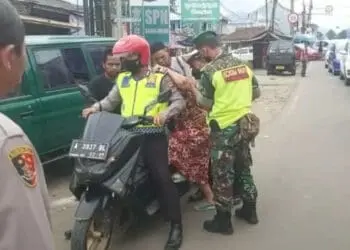 Personel Polri dan TNI, sedang menaikan nenek-nenek ke motor untuk diantarkan ke RSUD Berkah Pandeglang, saat terjebak macet di Jalan Raya Mengger-Caringin, Selasa (3/5/2022). (ISTIMEWA)