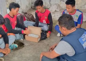 Giwan, didampingi teman-temannya sedang membuka dus untuk melihat sepasang sepatu, yang diberikan relawan Laznas Rumah Yatim, Senin (18/7/2022). (ISTIMEWA)