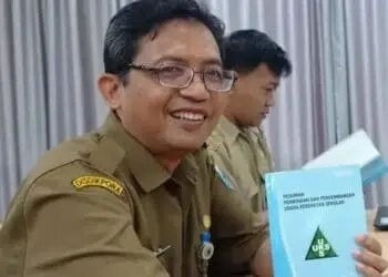 Sambil senyum sumringah, Sekretaris Dindikpora Pandeglang, Sutoto, menujukkan buku UKS yang sedang dipelajarinya. (ISTIMEWA)