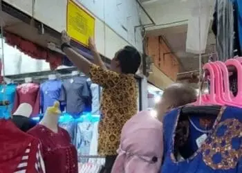 Pihak Diskoperindag Pandeglang, menempelkan stiker peringatan keras di kios yang belum bayar sewa, Jumat (15/7/2022). (ISTIMEWA')