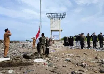 Para mahasiswa KKN STAISMAN Pandeglang, bersama aparatur Desa Teluk, sedang upacara diatas tumpukan sampah di Pantai Teluk Labuan, Senin (22/8/2022). (ISTIMEWA)