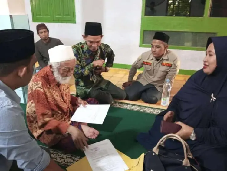 Abuya KH. Muhtadi Dimyati Cidahu, sedang membubuhkan tanda tangannya di secarik kertas, sebagai bukti merestui dan mendukung penuh kegiatan HSN 2022 di Pandeglang. (ISTIMEWA)