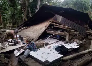 RUMAH ROBOH–Wanita paruh baya, sedang merapikan barang – barang berharga miliknya, pasca rumahnya roboh rata dengan tanah, Kamis (2/2/2023). (ISTIMEWA)