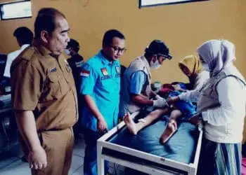 MENINJAU: Proses khitanan massal di Aula Desa Ranca Iyuh, Kecamatan Panongan, Senin (8/5). Terlihat ketua KNPI Kabupaten Tangerang sedang meninjau langsung salah satu anak yang terbaring di tempat tidur sedang dalam proses khitan. (ALFIAN HERIANTO)