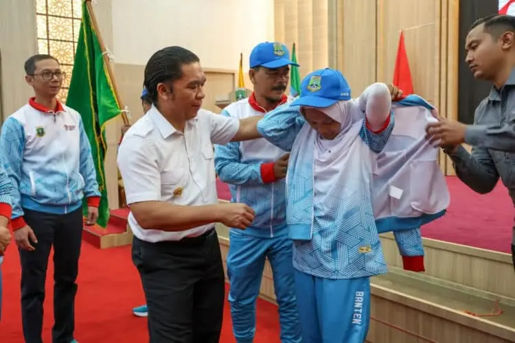 Pj Gubernur Banten Al Muktabar, secara simbolis menyematkan seragam kepada salah satu atlet. (ISTIMEWA)