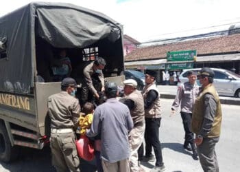 TERJARING RAZIA: Petugas Satpol PP dan Dinsos Kabupaten Tangerang bersama anggota Polresta Tangerang, sedang mengangkut salah satu PMKS ke mobil di Jalan Raya Serang, Desa Cikupa, Kecamatan Cikupa, Selasa (5/3). (ALFIAN HERIANTO)