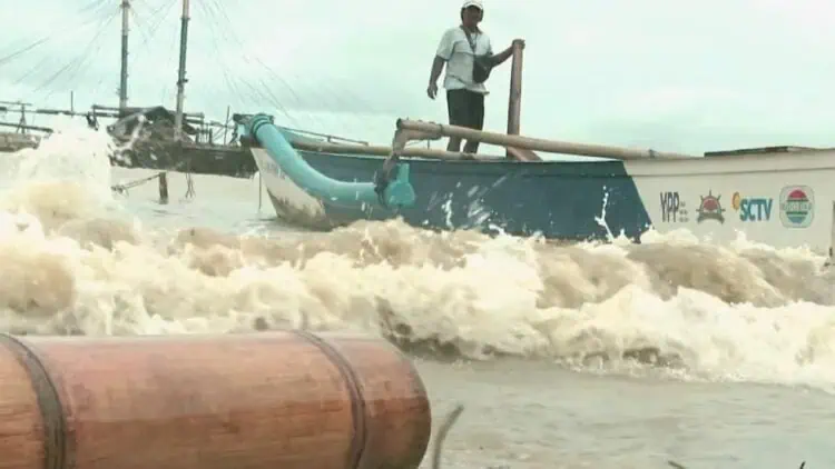 Seorang nelayan memeriksa perahu, di tengah gelombang ombak tinggi di Perairan Selat Sunda. (ISTIMEWA)