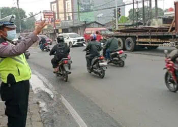 ATUR LALU LINTAS: Seorang anggota Polisi sedang mengatur arus lalu lintas (Lalin) di Jalan Raya Serang, Desa Cibadak, Kecamatan Cikupa. (DOK/SATELIT NEWS)