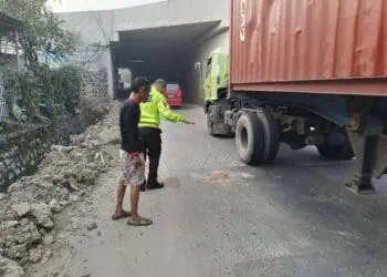 Seorang petugas kepolisian, tengah menunjukan lokasi terjadinya kecelakaan pengendara motor. (ISTIMEWA)