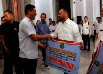 MENYERAHKAN BANTUAN : Kepala BPBD Provinsi Banten Deden Apriandhi Hartawan (kiri), menyerahkan bantuan kemanusiaan dari Pemprov Banten, secara simbolis, Rabu (3/12/2025) malam. (ADIB FAHRIE/SATELITNEWS.COM)