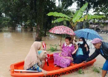 Kepala Desa (Kades) Idaman, Kecamatan Patia, Kabupaten Pandeglang, Ilman, dibantu perangkat desa mengantar ibu hamil ke Bidan Desa, disaat kondisi tengah banjir, Kamis (22/1/2026). (ISTIMEWA)