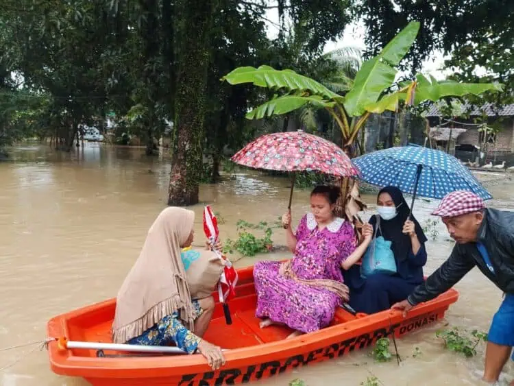 Kepala Desa (Kades) Idaman, Kecamatan Patia, Kabupaten Pandeglang, Ilman, dibantu perangkat desa mengantar ibu hamil ke Bidan Desa, disaat kondisi tengah banjir, Kamis (22/1/2026). (ISTIMEWA)