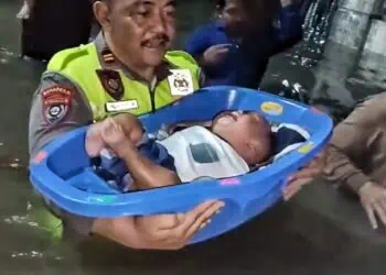MENGEVAKUASI ANAK : Personel Polres Cilegon Polda Banten, mengevakuasi seorang anak yang rumah orang tuanya terendam banjir. (ISTIMEWA)