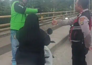 Tukang ojek online bersama anggota Polsek Cisauk membujuk seorang wanita yang hendak terjun ke bawah jembatan. (ISTIMEWA)