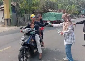 BAGIKAN MASKER - Tim Nakes dan pegawai Puskesmas Labuan bersama relawan, membagikan masker kepada pengendara yang melintas, Minggu (6/9/2026). (ISTIMEWA)