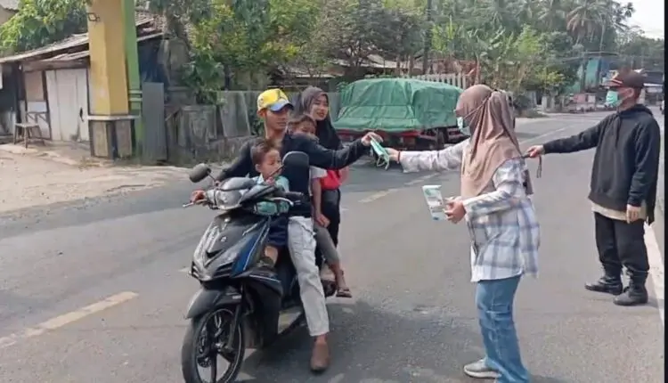 BAGIKAN MASKER - Tim Nakes dan pegawai Puskesmas Labuan bersama relawan, membagikan masker kepada pengendara yang melintas, Minggu (6/9/2026). (ISTIMEWA)