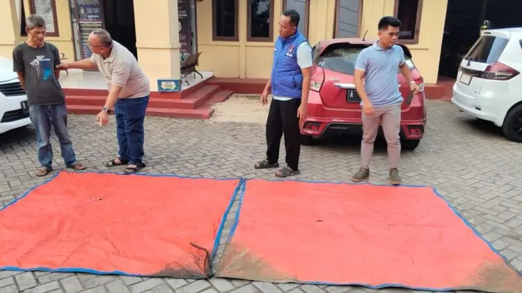 TERPAL : Anggota Polda Banten, menunjukkan terpal hasil temuan pencarian rombongan jurnalis yang hilang di Perairan Selat Sunda. (ISTIMEWA)