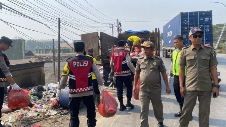 BERSIHKAN SAMPAH -- Petugas Polisi dari Polsek Cikande Polres Serang, bersama personel Dinas Kebersihan dan Pemerintah Kecamatan (Pemkec) Cikande, membersihkan tumpukan sampah liar di tepi Jalan Raya Serang-Jakarta, Desa Parigi, Kecamatan Cikande, Selasa (15/9/2026). (ISTIMEWA)