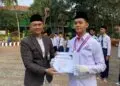 SIMBOLIS: Katib Ma’had Tarbiyatul Mubtadiin, H. Mohamad Saepudin, secara simbolis memberikan sertifikat penghargaan kepada salah satu santri berprestasi di ajang Olimpiade Madrasah Indonesia (OMI) 2026. (ISTIMEWA)